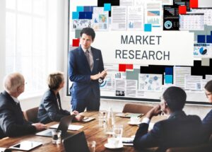 A business professional presenting market research data to a group of colleagues in a conference room setting.
